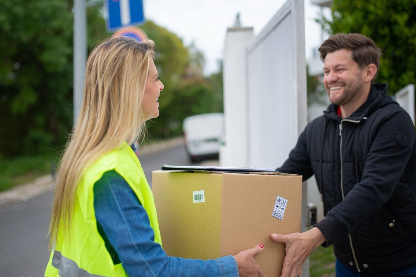 A customer receiving a parcel from a courier in a hi-vis vest