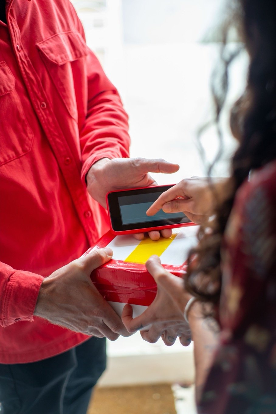 A courier collecting a signature on a handheld device at the door
